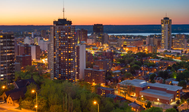 View of downtown Hamilton at dusk, with Lake Ontario in the background.