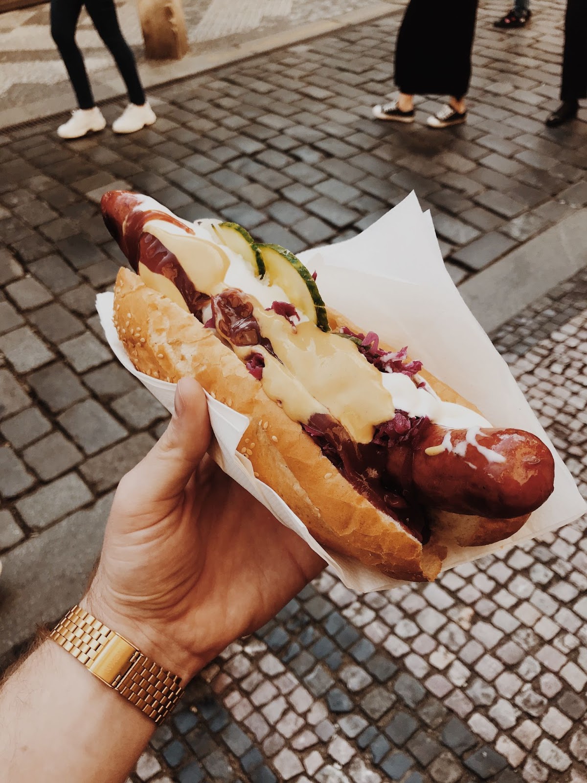 A customer holding a hotdog loaded with toppings.