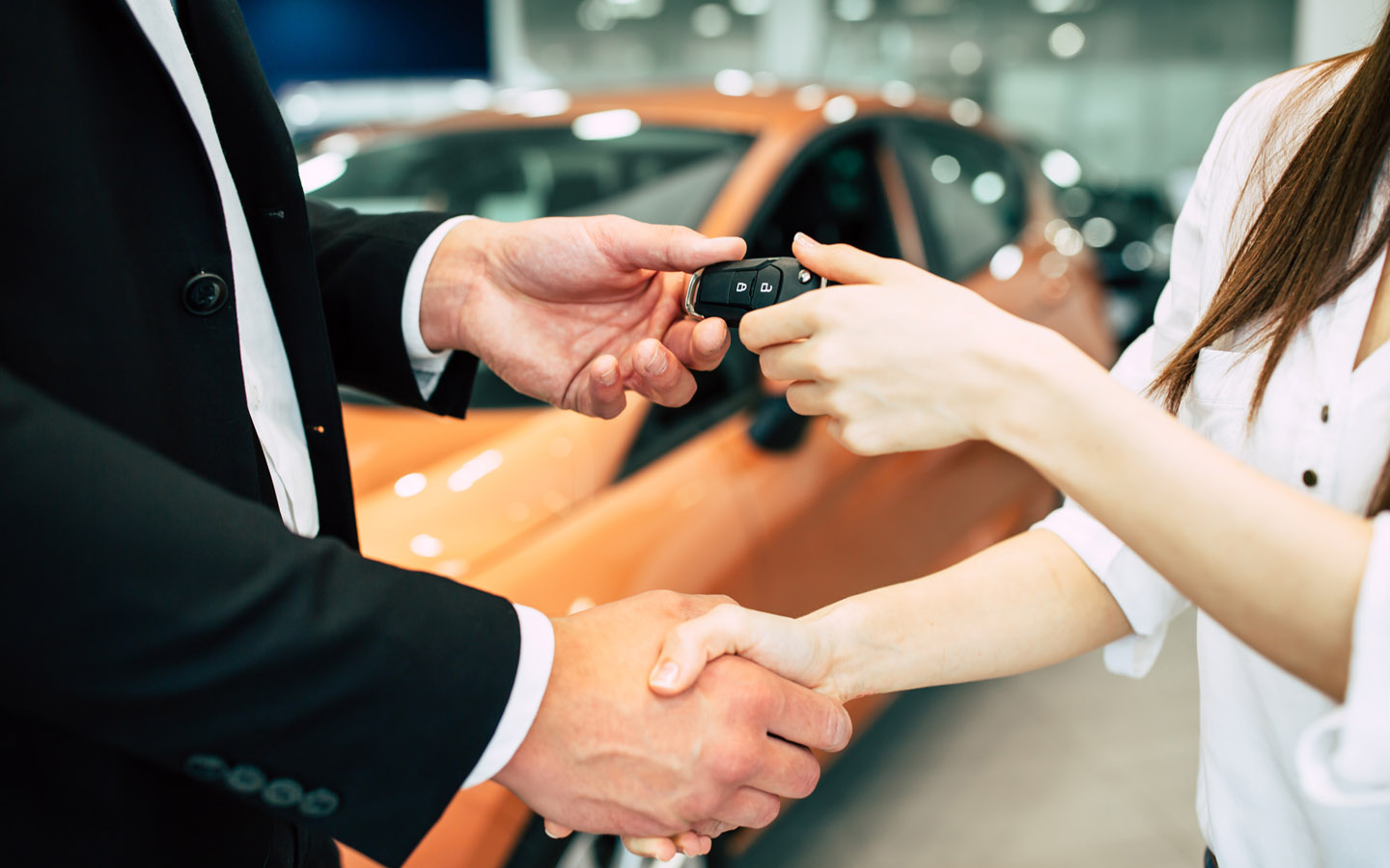 woman taking car keys from retailer after negotiating a car lease agreement 