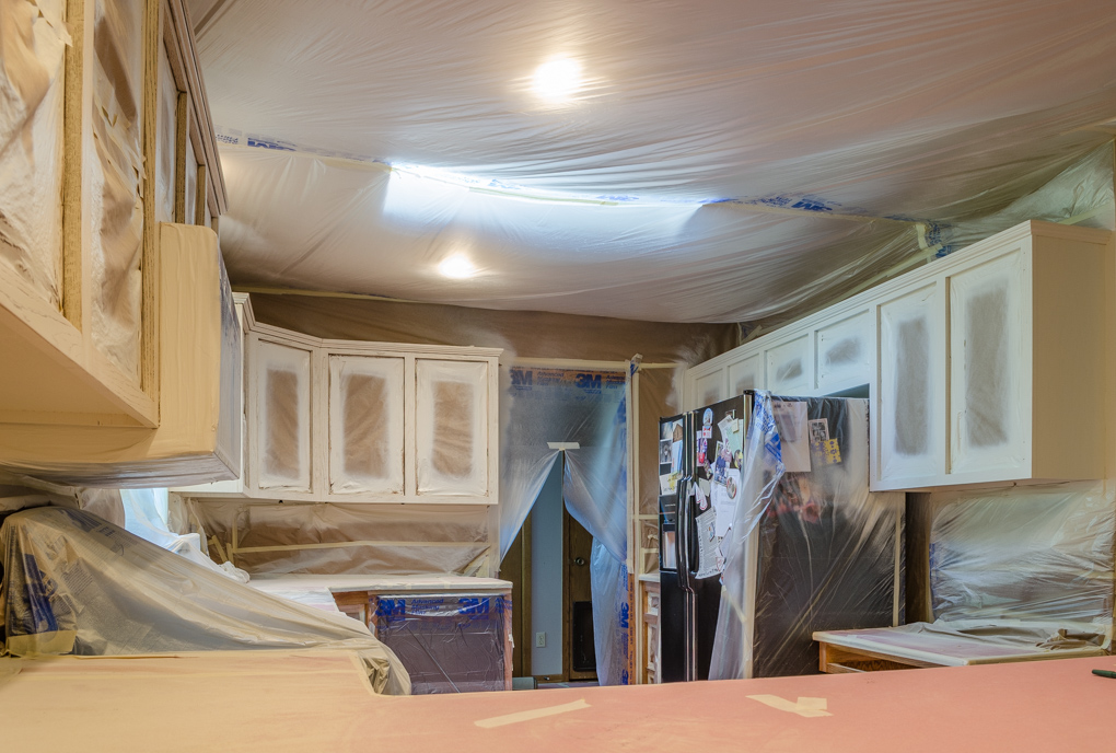 A kitchen taped and masked off completely with plastic, in preparation to be sprayed. 