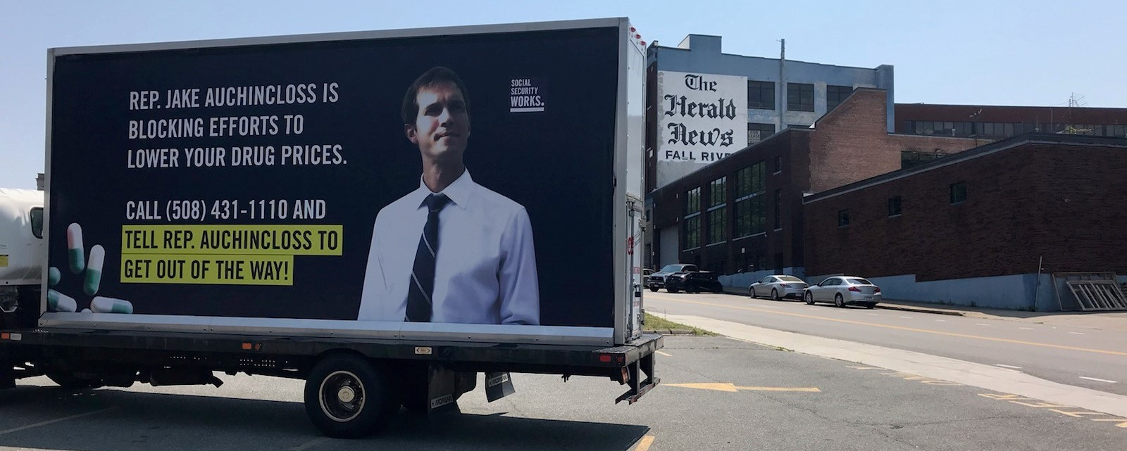 Image of the Billboard truck, reading "Rep. Jake Auchincloss is blocking efforts to lower your drug prices. Call 508-431-1110 and tell Rep. Auchincloss to get out of the way!"