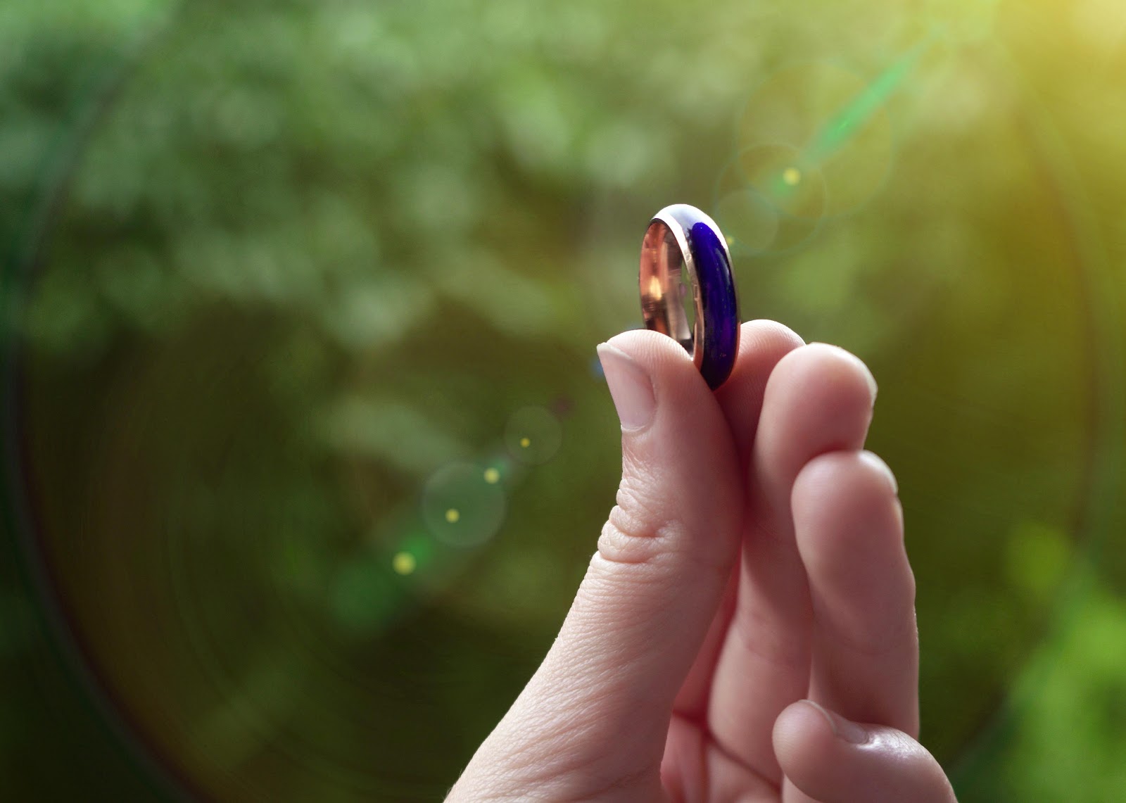 Person's hand holding a color-changing vintage blue mood ring.