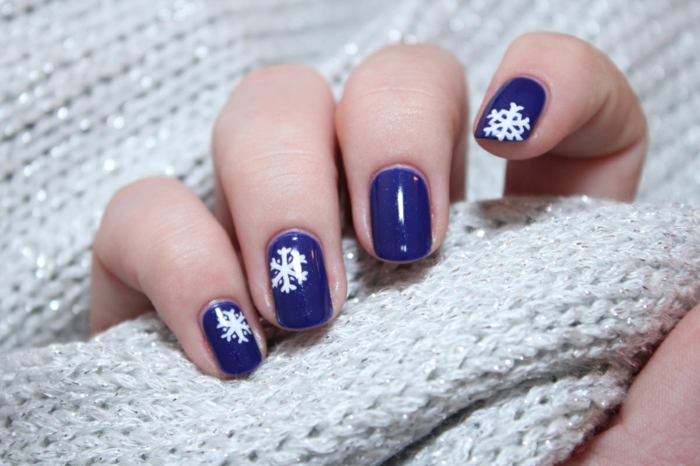 Weiße Schneeflocken auf dunkelblauem Grund, ovale Nagelform, schöne Idee für Winternägel zum Nachstylen