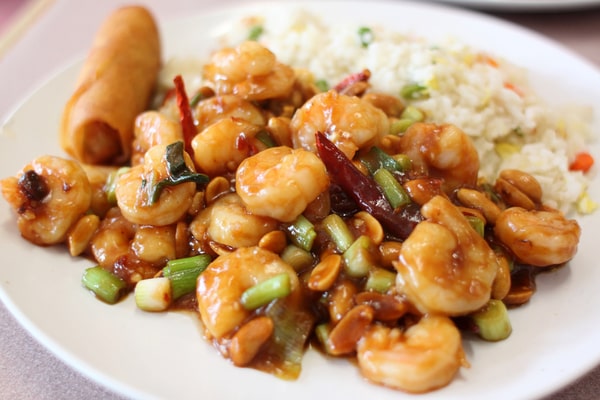 A plate of kung pao shrimp, egg roll, and fried rice