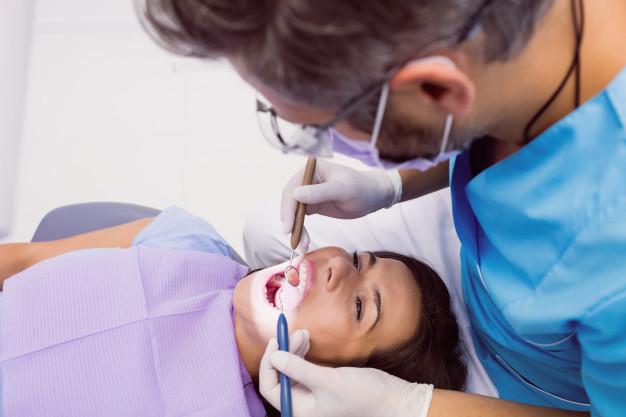 Dentist examining a female patient with tools Free Photo
