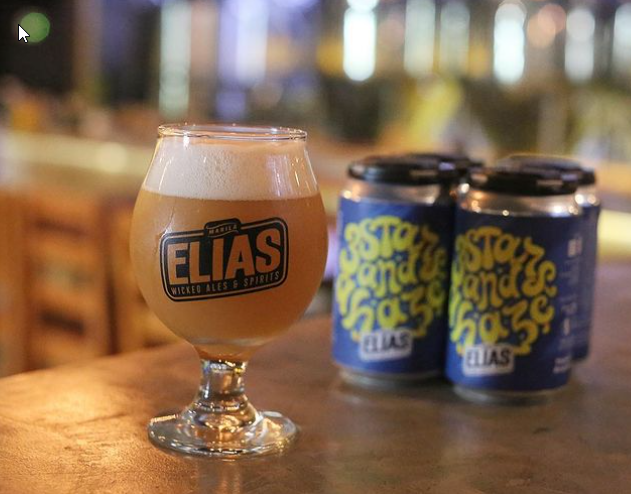 A glass of Elias beer beside cans