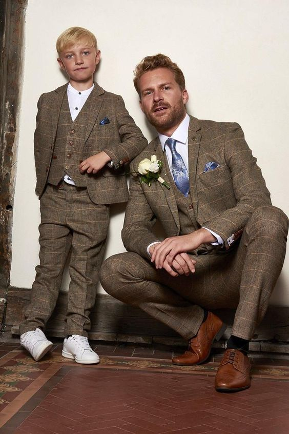 A man and a boy are wearing the same suit and the boy is wearing white sneakers