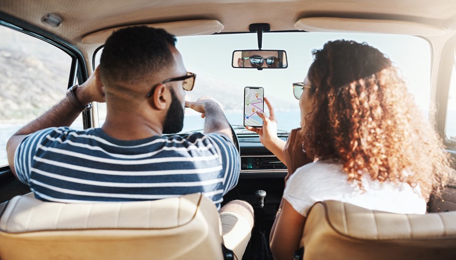 Two people looking at a map on their phone while driving