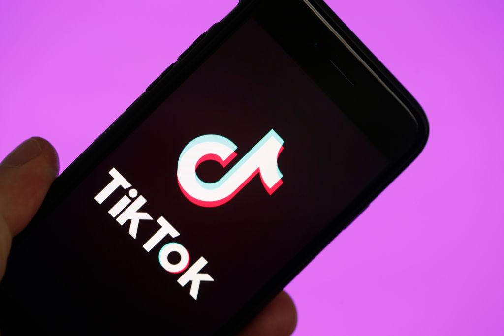 Logo de TikTok sur un téléphone intelligent iPhone, sur fond mauve.