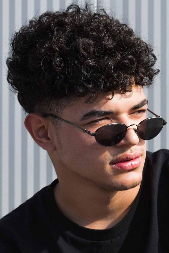 a man rocking curly hairstyles for men with a pair of sunglasses