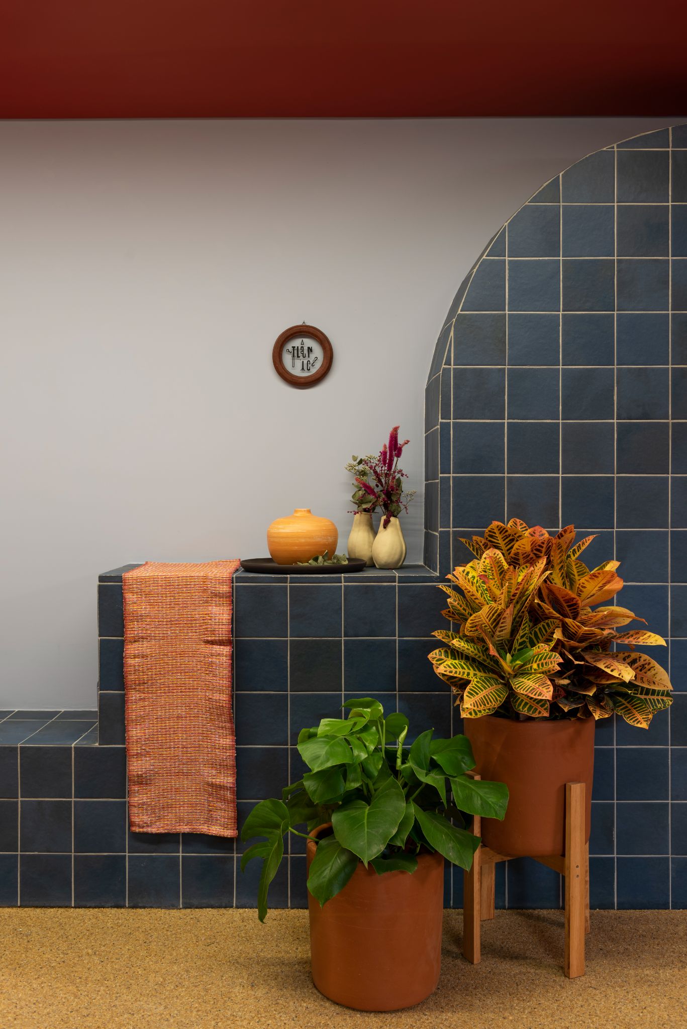 Ambiente com tapete cor de areia, parede revestida com cerâmica azul, vasos de plantas e parede branca