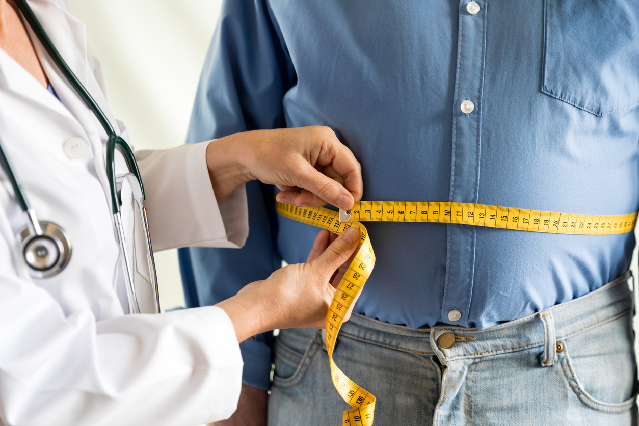 Médico midiendo la cintura y la barriga de un hombre con una cinta métrica