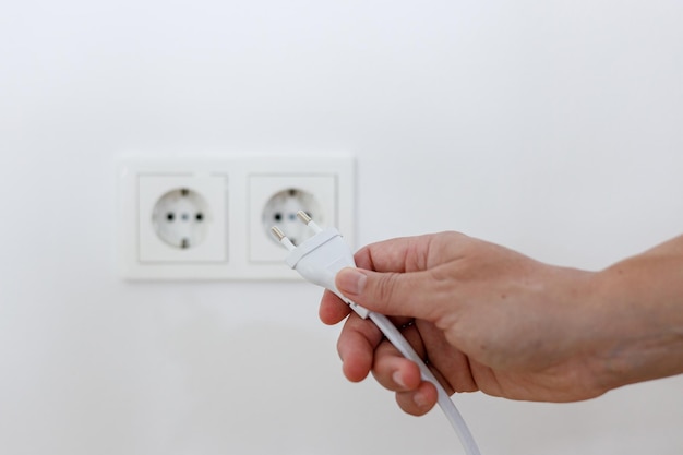 Electric plug in a hand on a white background