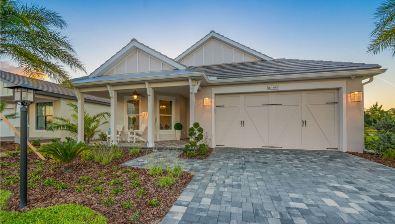 A single-story, beige-colored home in Lakewood Ranch with a detailed stone driveway and carriage house garage door.