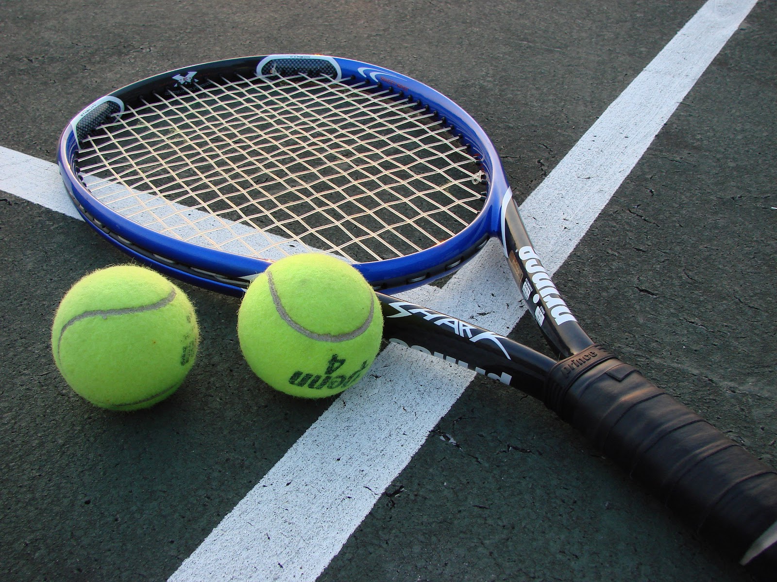 image of a tennis racquet and two green tennis balls