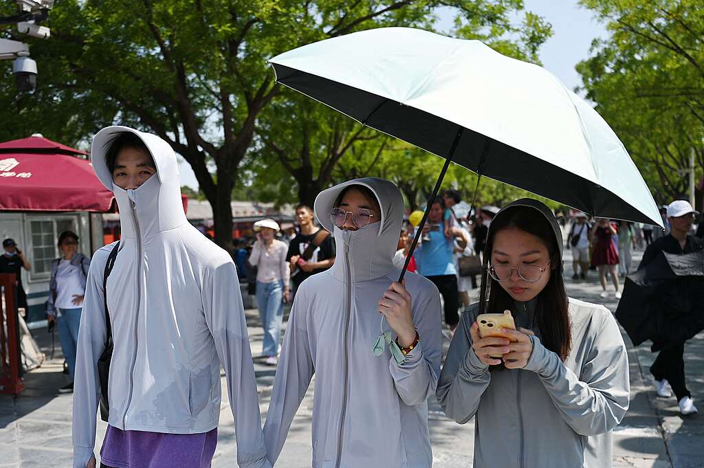 People shelter from the sun under an umbrella as they arrive to visit the Forbidden City during a heatwave in Beijing on June 24, 2023. Beijing recorded its third consecutive day of 40 degree Celsius weather, the first time since records began. © GREG BAKER/AFP via Getty Images