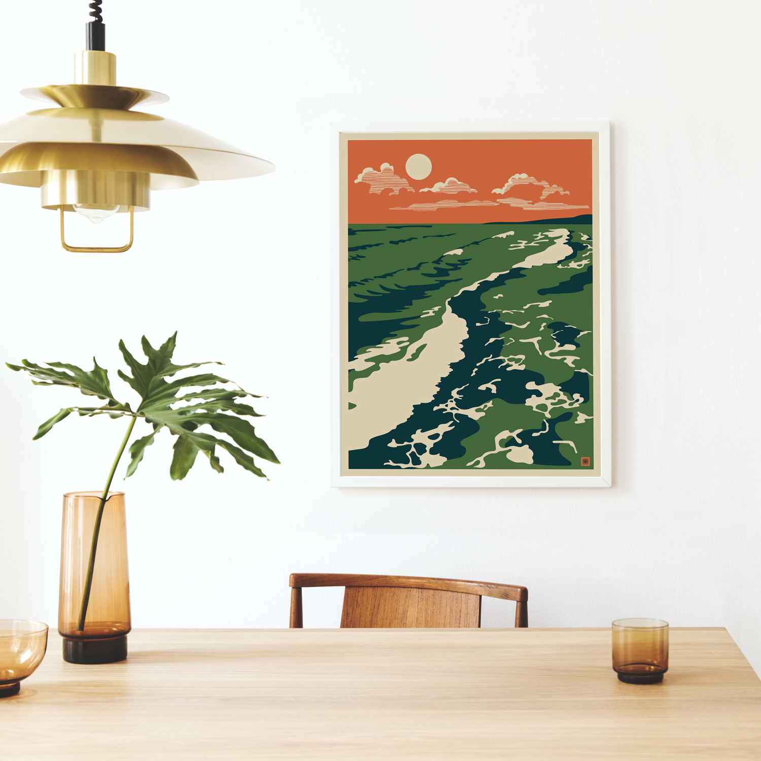 photo of a desk with a plant and a cup with a graphic print on the wall of a beach scene