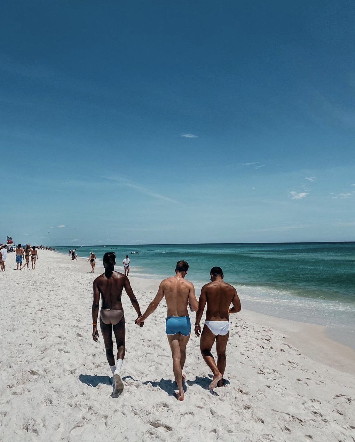 Three men walking on the beach.