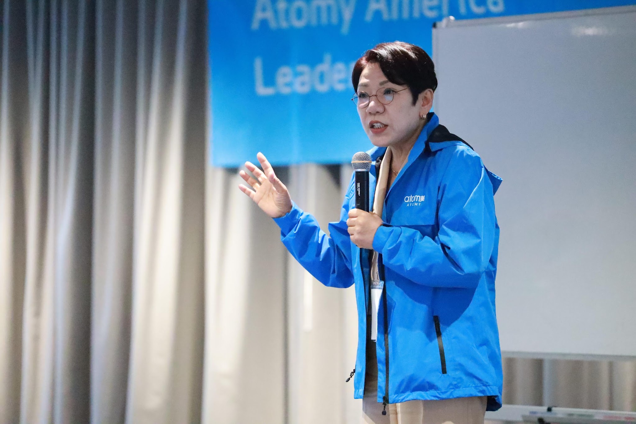 A person in a blue jacket holding a microphone

Description automatically generated