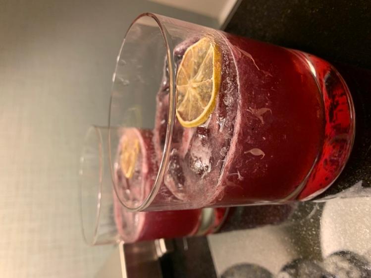 A glass of red liquid with a slice of lemon on top

Description automatically generated with medium confidence