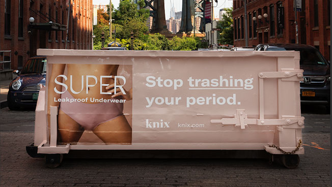 Knix mobile dumpster that has a picture of a woman in her underwear and the message "Stop trashing your period".