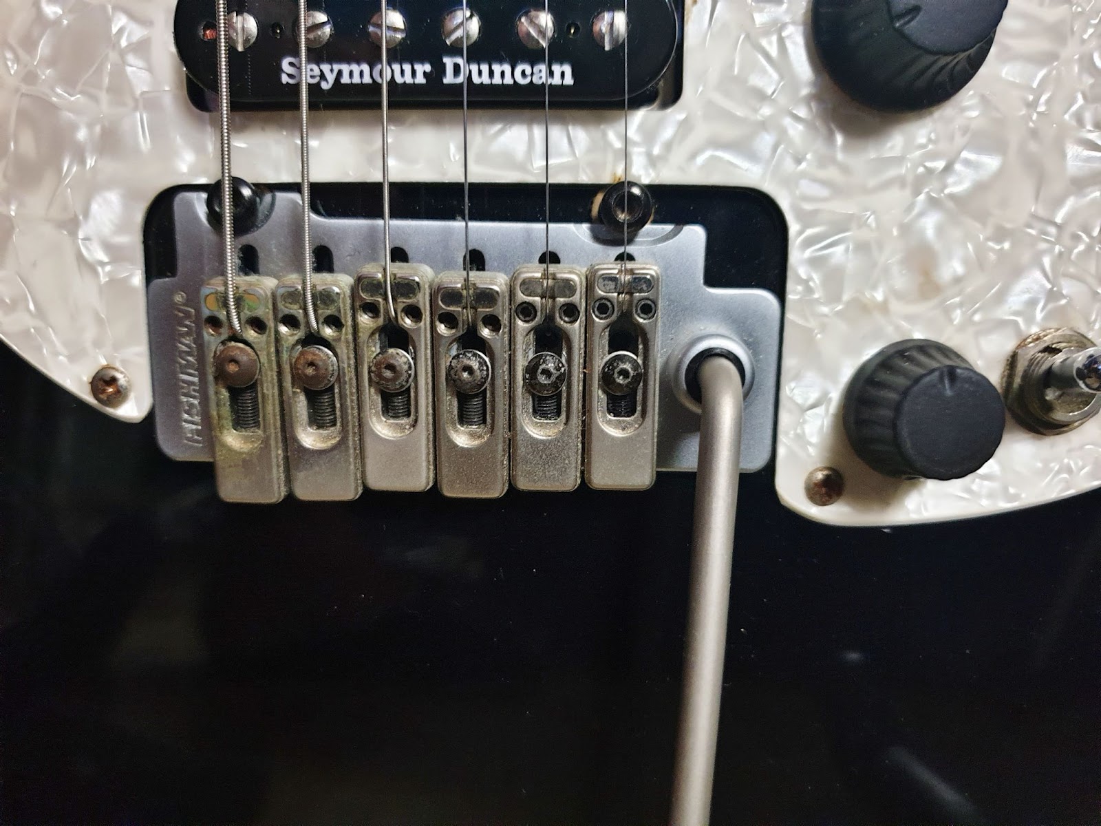 A close up picture of the bridge of a Parker P38 showing the piezo pickups.