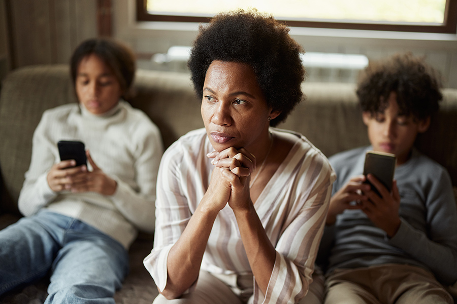 Concerned parent between two children using smartphones