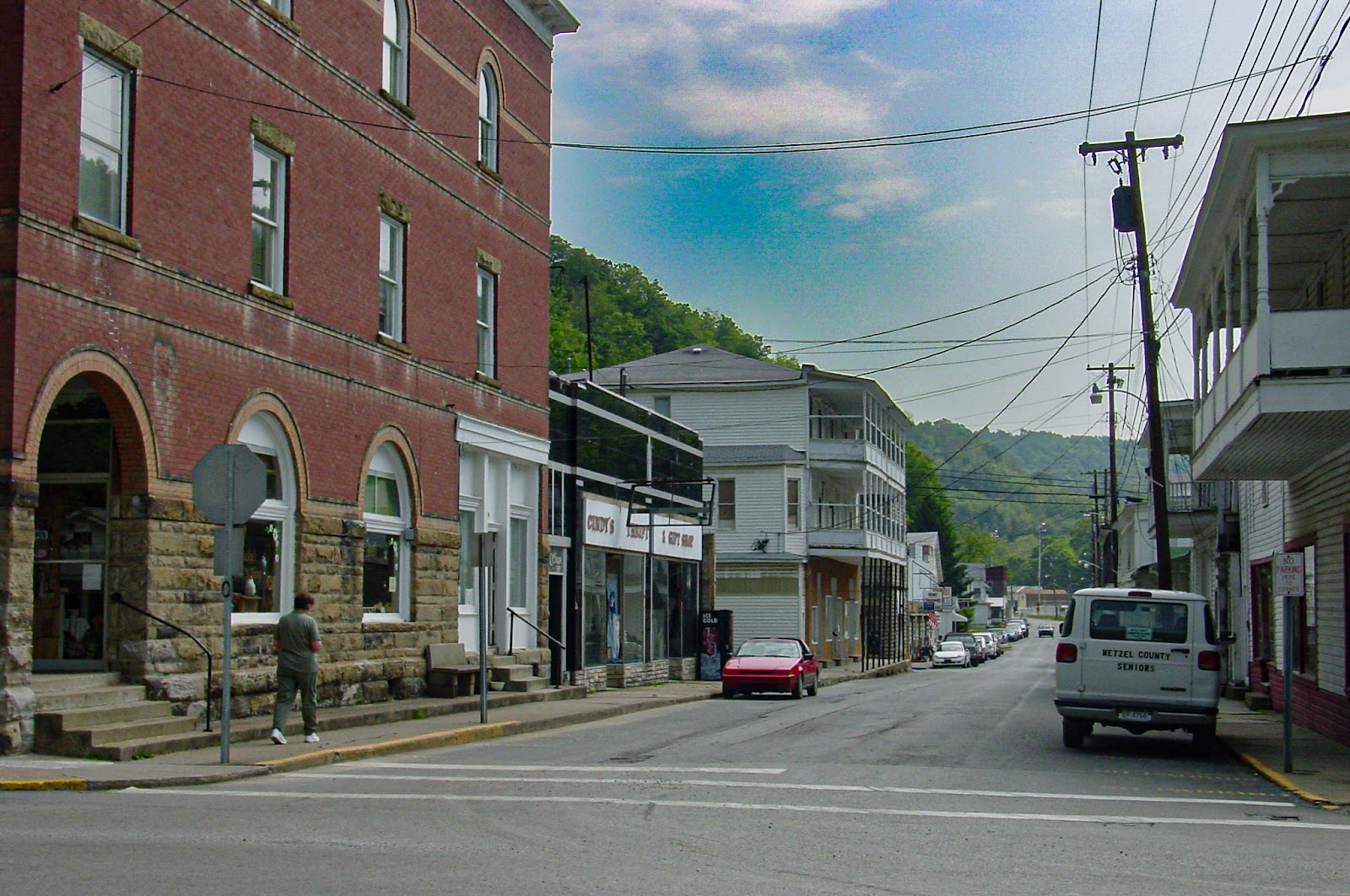 A small town with red brick 3-story building on a 2-lane highway. 