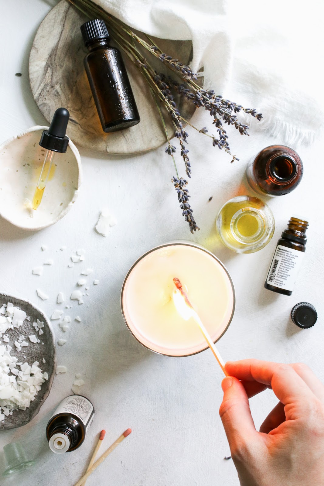 Lighting a candle amidst essential oils and lavender sprigs, creating a calming and aromatic ambiance.