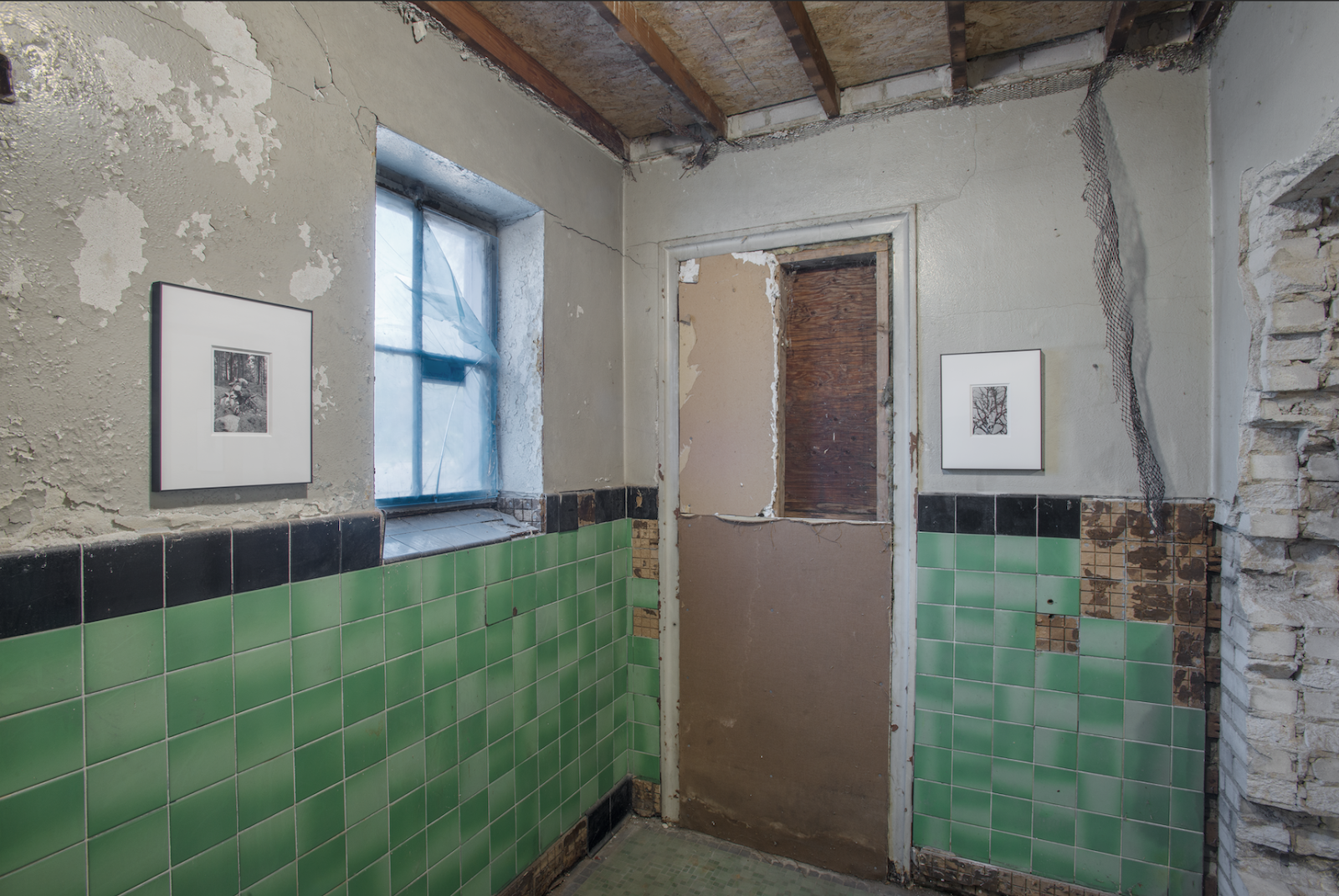 Image: Tetsuya Yamada, 3801 PARK AVE. TEMPORARY, May 20 – May 21, 2016. The inside of a dilapidated gas station with green tile on the bottom half of the walls while paint on the upper half chips and rips. The architecture is exposed. Two framed photos hang on the walls. Image courtesy of the artist.  