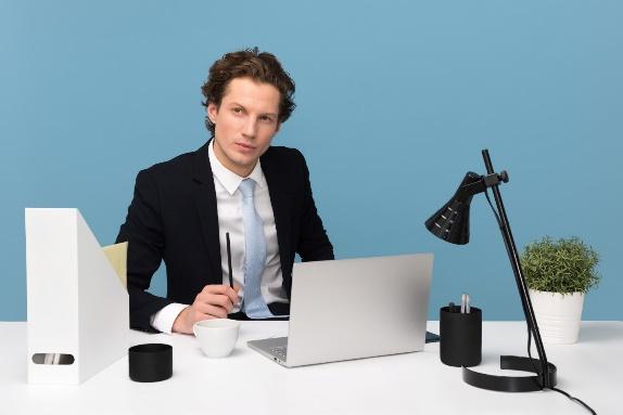 A person sitting at a desk with a computer and a microphone

Description automatically generated with medium confidence