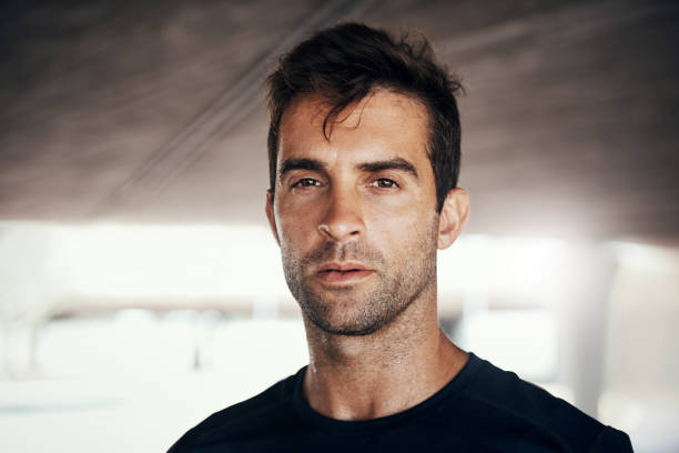 A closeup portrait of a man with trimmed beard in black t-shirt