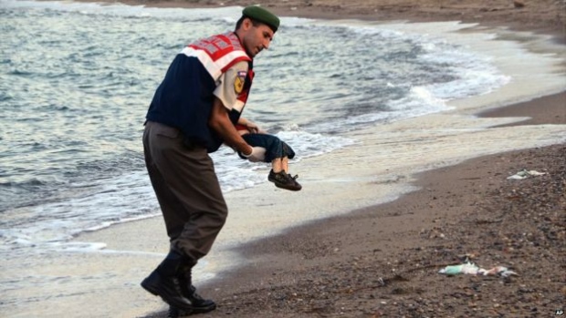 A paramilitary police officer carries the lifeless body of Alan Kurdi,  one of a dozen Syrian civil war refugees who drowned off the coastal town of Bodrum after a failed attempt to cross the Mediterranean on two boats bound for the Greek island of Kos.