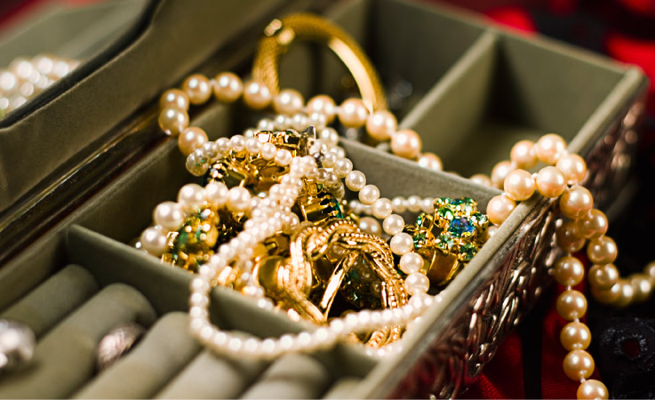 A close-up of a jewelry box with pearls and various pieces of gold jewelry.