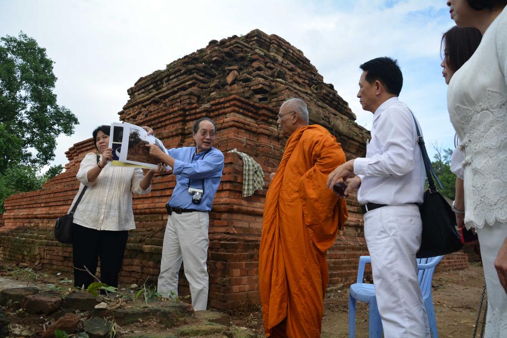 U Mickey Heart, second from left, shows a Thai group what some believe is the tomb of King Udumbara at Lin Zin Khon Cemetery in Amarapura on October 3, 2014. (Teza Hlaing | Frontier)