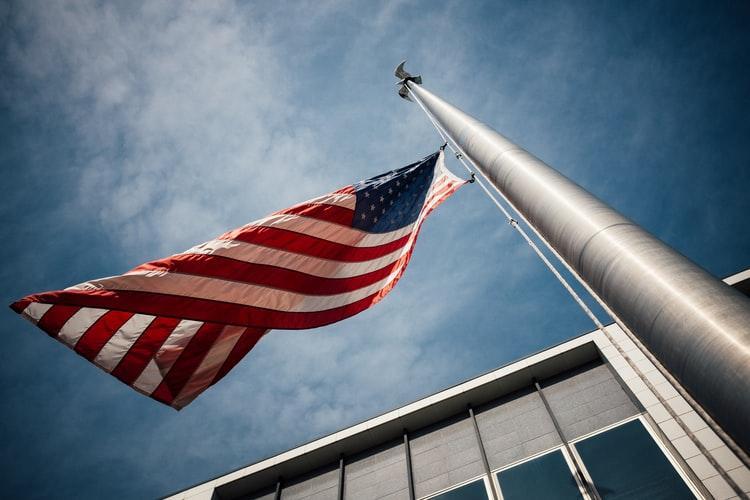 Picture of the American Flag on a flag pole in front of a house