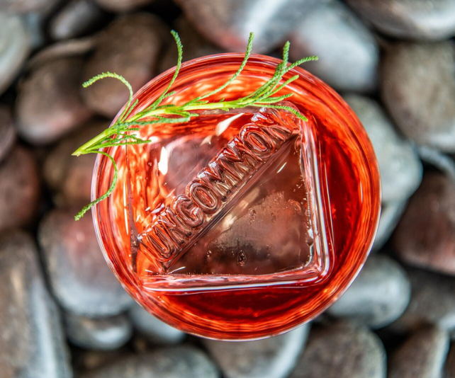 A top-down view of a negroni with an Uncommon stamp on the ice cube