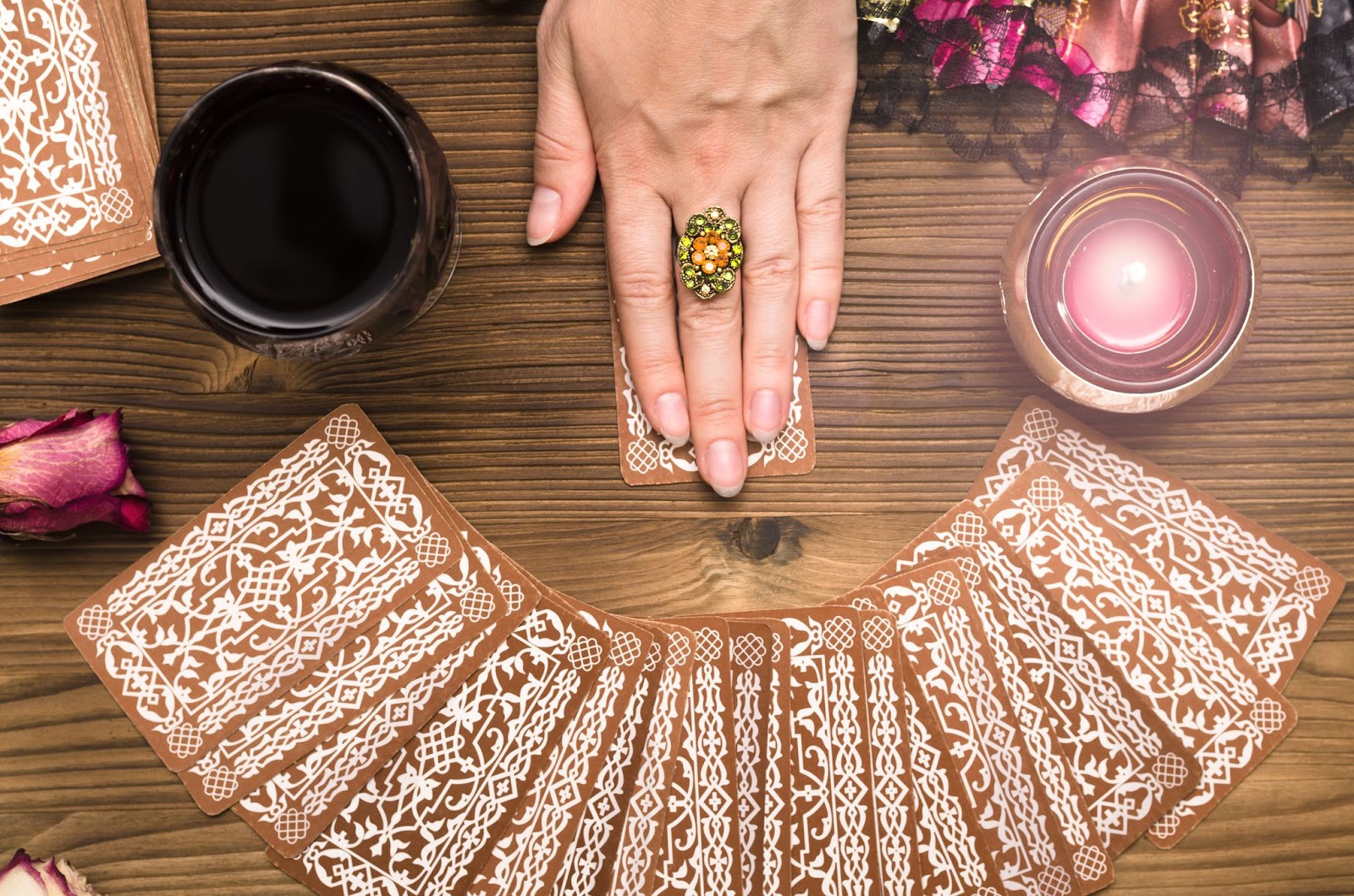 A spread of tarot cards with a woman's hand hovering over one card.