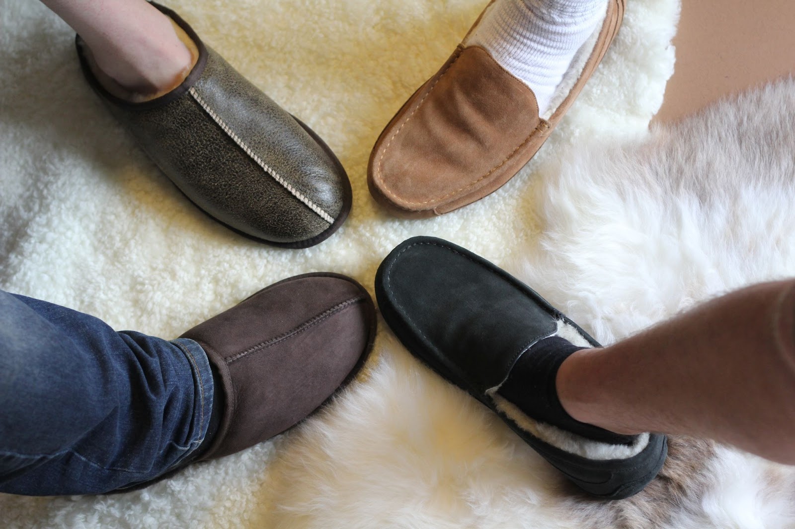 4 men's feet wearing different styles of sheepskin slippers in shades of brown and black