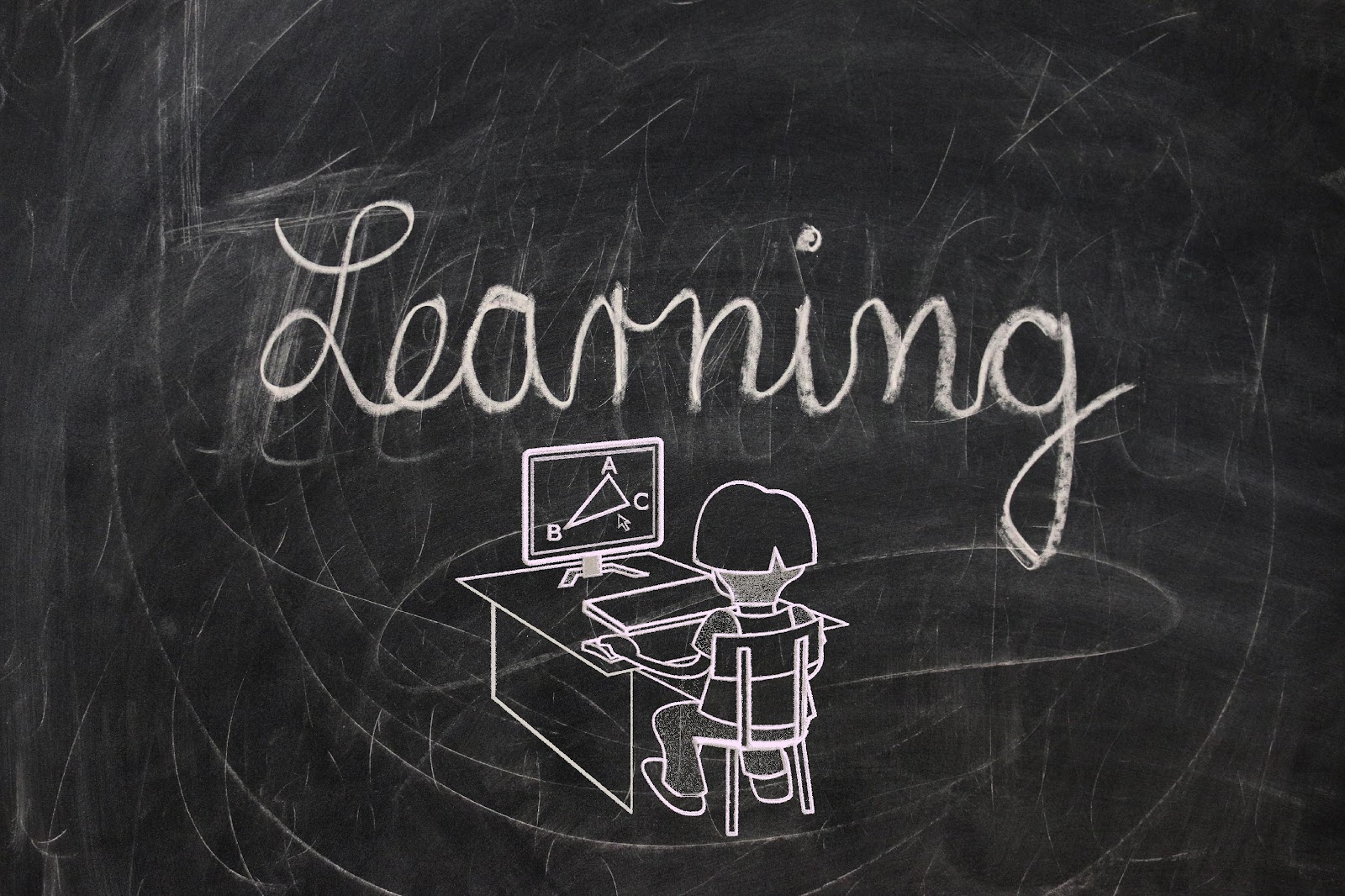 Black chalkboard with an image of a young child sitting at a desk with the word "learning" in cursive drawn in white chalk