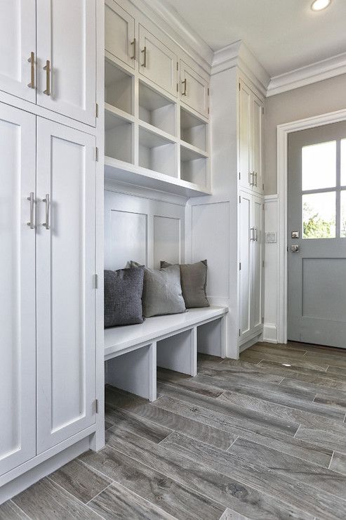 white mudroom with grey floors, grey door, and white cabinets