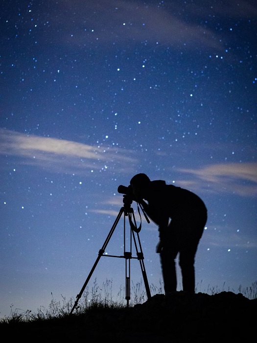 Silhouette of photographer with camera on a tripod at night