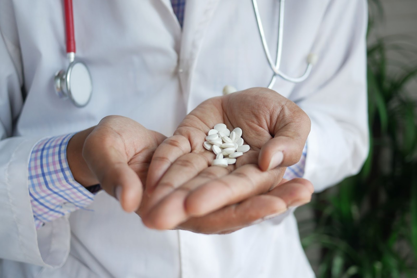Male doctor in lab coat holds white pills in hands, indicating supplementation option to combat vitamin d deficiency and infertility that can be associated with it.