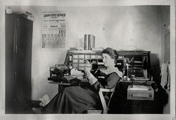 black and white photo of a woman in an office chair at a desk