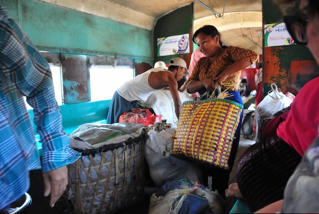 A woman loads bags full of vegetables on to a train carriage in Yangon. Many use the slow-moving passenger trains to transport goods that they will sell in outlying villages, since few can afford road transportation. Credit: Amantha Perera/IPS