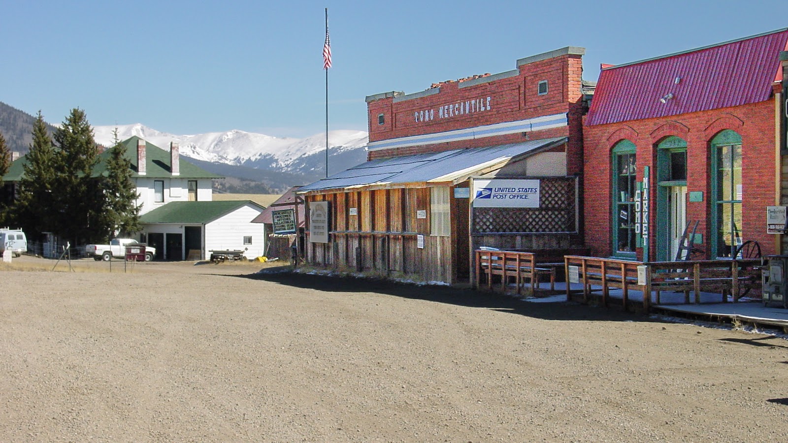 Small town store with dirt streets and snowy mountains.