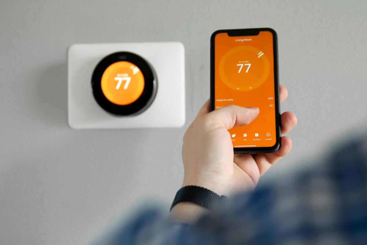A person adjusting the setting on their smart thermostat from their phone.
