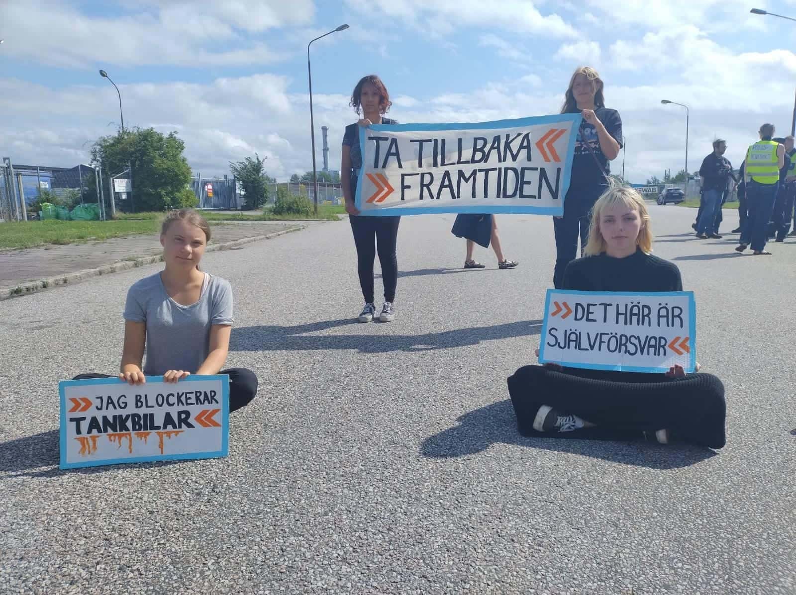 Greta Thunberg sits with three other young activists across a road