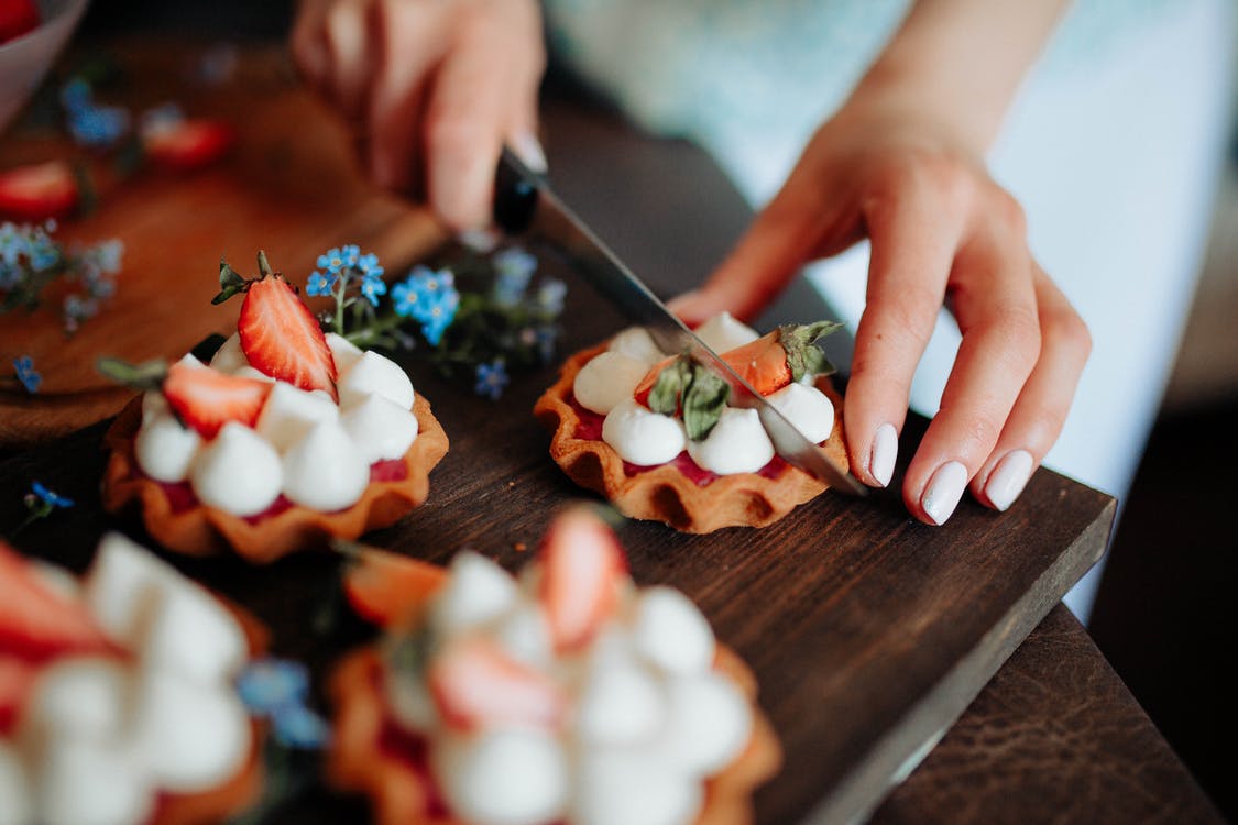 Crop woman cutting cake with berries