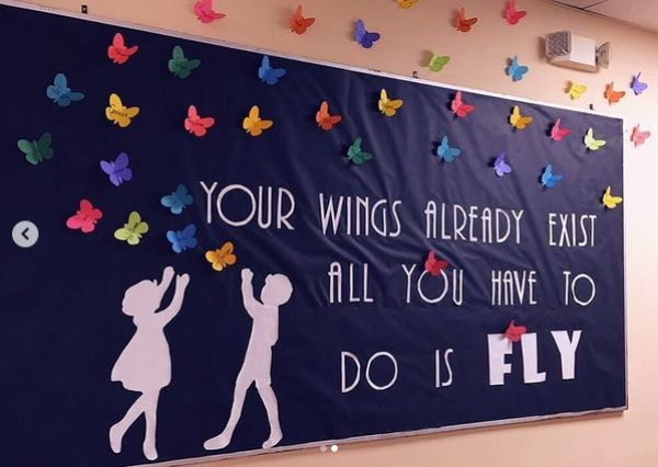 a blue bulletin board full of colored butterflies with the caption - our wings already exist; all you have to do is fly